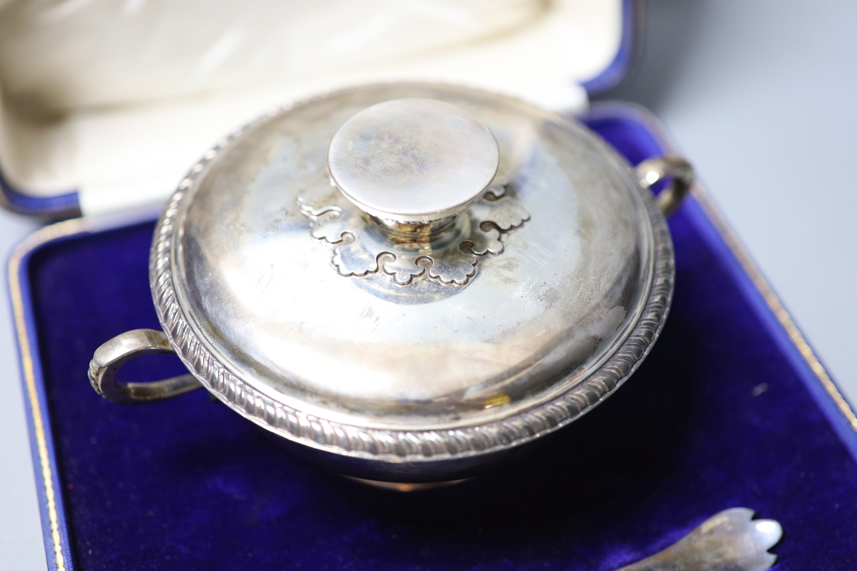 A cased George V silver porringer cup and cover, Carrington & Co, London, 1924, diameter 18.3cm, together with a rat tail trefid spoon, Francis Higgins & Sons Ltd, London, 1924, 170z.